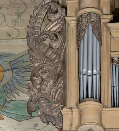 Zdjęcie nr 5: Organy architektoniczne, pięcioosiowe na wysokiej podstawie i niewielkim cokole, trójwieżyczkowe. Wieżyczki boczne niższe od środkowej, wszystkie z półokrągłymi ryzalitami, z prostokątnymi i wypukłymi prześwitami na piszczałki, dekorowanymi w górnych narożach akantem, zakończone fryzem i gzymsem oraz ornamentalnymi szczytami utworzonymi z akantu, karbowanej wstęgi, kampanul i muszli; ryzality u spodu z podwieszonymi kampanulami i muszlą. Szczyt środkowej wieżyczki utworzony z ornamentu małżowinowo-chrząstkowego. Pomiędzy wieżyczkami dwie najniższe osie z prześwitami na piszczałki w formie stojącego prostokąta, zakończone fragmentami gzymsu. Organy ujęte uszami utworzonymi z akantu i karbowanej wstęgi. Struktura polichromowana w całości w kolorze ciemnobeżowym, ornamenty złocone.