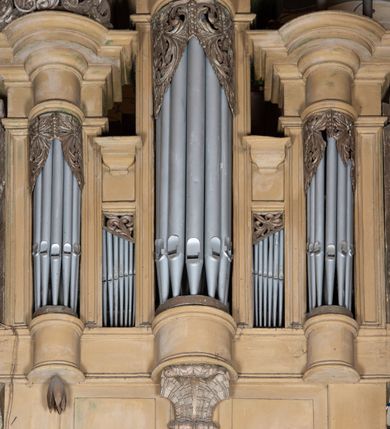 Zdjęcie nr 4: Organy architektoniczne, pięcioosiowe na wysokiej podstawie i niewielkim cokole, trójwieżyczkowe. Wieżyczki boczne niższe od środkowej, wszystkie z półokrągłymi ryzalitami, z prostokątnymi i wypukłymi prześwitami na piszczałki, dekorowanymi w górnych narożach akantem, zakończone fryzem i gzymsem oraz ornamentalnymi szczytami utworzonymi z akantu, karbowanej wstęgi, kampanul i muszli; ryzality u spodu z podwieszonymi kampanulami i muszlą. Szczyt środkowej wieżyczki utworzony z ornamentu małżowinowo-chrząstkowego. Pomiędzy wieżyczkami dwie najniższe osie z prześwitami na piszczałki w formie stojącego prostokąta, zakończone fragmentami gzymsu. Organy ujęte uszami utworzonymi z akantu i karbowanej wstęgi. Struktura polichromowana w całości w kolorze ciemnobeżowym, ornamenty złocone.