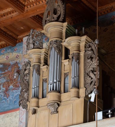Zdjęcie nr 3: Organy architektoniczne, pięcioosiowe na wysokiej podstawie i niewielkim cokole, trójwieżyczkowe. Wieżyczki boczne niższe od środkowej, wszystkie z półokrągłymi ryzalitami, z prostokątnymi i wypukłymi prześwitami na piszczałki, dekorowanymi w górnych narożach akantem, zakończone fryzem i gzymsem oraz ornamentalnymi szczytami utworzonymi z akantu, karbowanej wstęgi, kampanul i muszli; ryzality u spodu z podwieszonymi kampanulami i muszlą. Szczyt środkowej wieżyczki utworzony z ornamentu małżowinowo-chrząstkowego. Pomiędzy wieżyczkami dwie najniższe osie z prześwitami na piszczałki w formie stojącego prostokąta, zakończone fragmentami gzymsu. Organy ujęte uszami utworzonymi z akantu i karbowanej wstęgi. Struktura polichromowana w całości w kolorze ciemnobeżowym, ornamenty złocone.