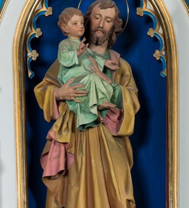 Zdjęcie nr 10: Ołtarz otrzymał formę drewnianej, przyściennej struktury architektonicznej ze zwieńczeniem o trójosiowym, jednokondygnacyjnym założeniu. Nastawa prezentuje się jako struktura polichromowana w odcieniach jasnej seledynowej zieleni, rozbielonego granatu oraz czerwieni. Partie ornamentów zostały wyzłocone. Drewniana mensa z portatylem wspiera się na prostopadłościennym stipesie ołtarzowym. Jego przód zdobią trzy czworoboczne płaszczyzny zbliżone do kwadratu ujęte profilowanymi, złoconymi listwami. W ich centrum umieszczono płaskorzeźbione, złocone czteroliście w diagonalnym układzie. Dwa w skrajnych płycinach utworzono ze stylizowanych liści akantu, natomiast środkowy przyjął formę geometryczno-roślinną. Retabulum ustawiono na wysokiej podstawie w kształcie nawiązującym do wydłużonego trapezu z wklęsłymi bokami, wspierającej się na krótszym boku. Podstawę zamyka u góry łamana, profilowana listwa. Jej lico artykułowane jest czterema zbliżonymi do kwadratu płycinami obramionymi złotymi, profilowanymi listwami. Ich środek zdobią takie same stylizowane, płaskorzeźbione i złocone czteroliście o diagonalnym układzie, wpisane w kwadrat. Na środku mensy, na tle podstawy, ustawiono czworoboczne tabernakulum w formie kapliczki z dwuspadowym dachem flankowanej dwiema sterczynami z pinaklami, wyrastającymi z wydłużonych prostopadłościennych, wąskich przypór. Drzwiczki tabernakulum zdobi motyw płaskorzeźbionego kielicha ze srebrzoną hostią wpisaną w stylizowaną ostrołukową arkadę z noskami. Na podstawie nastawy wspiera się niski cokół zamknięty u góry fryzem z rytmicznie rozmieszczonymi, niewielkimi, płaskorzeźbionymi i złoconymi czterolistnymi rozetkami. Z cokołu wyrastają trzy ostrołukowe arkady o profilowanych krawędziach, w górnych częściach z wpisaną arkaturą, ozdobione płaskorzeźbionymi, złoconymi czołgankami, zwieńczone pinaklami. Arkada środkowa jest wyższa od flankujących ją arkad bocznych. Zdobi ją po bokach płaskorzeźbione obramienie z motywem złoconej wici roślinno-ornamentalnej. Ostrołukowe zamknięcie arkady wypełniono ażurowym maswerkiem z motywem czteroliścia wpisanego w koło, ujętego dwoma trójliściami. Wszystkie trzy arkady flankują smukłe sterczyny wyrastające z prostopadłościennych, wąskich przypór ustawionych na niskich cokolikach. Sterczyny przechodzą w pinakle zwieńczone kwiatonami. Dekorują je płaskorzeźbione i złocone czołganki. W przypadku arkad bocznych pomiędzy cokolikami wprowadzono podłużne płyciny ze stylizowanymi maswerkami, natomiast w arkadzie centralnej umieszczono niewielkie, diagonalne czteroliście. W polu środkowej arkady prezentowany jest obraz Matki Boskiej Niepokalanie Poczętej w płaskorzeźbionej, złoconej, drewnianej sukience wotywnej, a na zasuwach wizerunek Przemienienia Pańskiego i św. Walentego. W arkadach bocznych retabulum ustawiono z lewej strony pełnoplastyczną, polichromowaną rzeźbę z masy gipsowej św. Józefa z Dzieciątkiem, a z prawej św. Antoniego Padewskiego, także z Dzieciątkiem Jezus. Zwieńczenie nastawy zostało również ukształtowane architektonicznie. Tworzą je trzy ażurowe kapliczki z pinaklami ustawione na osiach retabulum. W kapliczce środkowej umieszczono pełnoplastyczną, polichromowaną figurę św. Franciszka z Asyżu z masy gipsowej. 