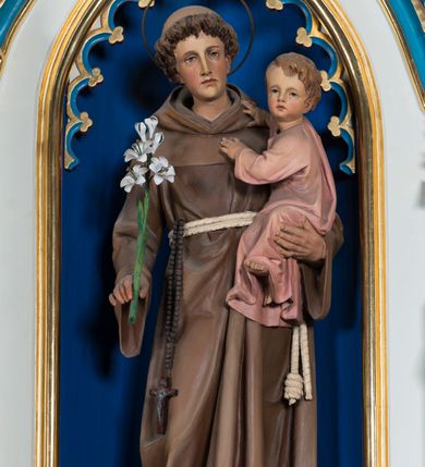 Zdjęcie nr 8: Ołtarz otrzymał formę drewnianej, przyściennej struktury architektonicznej ze zwieńczeniem o trójosiowym, jednokondygnacyjnym założeniu. Nastawa prezentuje się jako struktura polichromowana w odcieniach jasnej seledynowej zieleni, rozbielonego granatu oraz czerwieni. Partie ornamentów zostały wyzłocone. Drewniana mensa z portatylem wspiera się na prostopadłościennym stipesie ołtarzowym. Jego przód zdobią trzy czworoboczne płaszczyzny zbliżone do kwadratu ujęte profilowanymi, złoconymi listwami. W ich centrum umieszczono płaskorzeźbione, złocone czteroliście w diagonalnym układzie. Dwa w skrajnych płycinach utworzono ze stylizowanych liści akantu, natomiast środkowy przyjął formę geometryczno-roślinną. Retabulum ustawiono na wysokiej podstawie w kształcie nawiązującym do wydłużonego trapezu z wklęsłymi bokami, wspierającej się na krótszym boku. Podstawę zamyka u góry łamana, profilowana listwa. Jej lico artykułowane jest czterema zbliżonymi do kwadratu płycinami obramionymi złotymi, profilowanymi listwami. Ich środek zdobią takie same stylizowane, płaskorzeźbione i złocone czteroliście o diagonalnym układzie, wpisane w kwadrat. Na środku mensy, na tle podstawy, ustawiono czworoboczne tabernakulum w formie kapliczki z dwuspadowym dachem flankowanej dwiema sterczynami z pinaklami, wyrastającymi z wydłużonych prostopadłościennych, wąskich przypór. Drzwiczki tabernakulum zdobi motyw płaskorzeźbionego kielicha ze srebrzoną hostią wpisaną w stylizowaną ostrołukową arkadę z noskami. Na podstawie nastawy wspiera się niski cokół zamknięty u góry fryzem z rytmicznie rozmieszczonymi, niewielkimi, płaskorzeźbionymi i złoconymi czterolistnymi rozetkami. Z cokołu wyrastają trzy ostrołukowe arkady o profilowanych krawędziach, w górnych częściach z wpisaną arkaturą, ozdobione płaskorzeźbionymi, złoconymi czołgankami, zwieńczone pinaklami. Arkada środkowa jest wyższa od flankujących ją arkad bocznych. Zdobi ją po bokach płaskorzeźbione obramienie z motywem złoconej wici roślinno-ornamentalnej. Ostrołukowe zamknięcie arkady wypełniono ażurowym maswerkiem z motywem czteroliścia wpisanego w koło, ujętego dwoma trójliściami. Wszystkie trzy arkady flankują smukłe sterczyny wyrastające z prostopadłościennych, wąskich przypór ustawionych na niskich cokolikach. Sterczyny przechodzą w pinakle zwieńczone kwiatonami. Dekorują je płaskorzeźbione i złocone czołganki. W przypadku arkad bocznych pomiędzy cokolikami wprowadzono podłużne płyciny ze stylizowanymi maswerkami, natomiast w arkadzie centralnej umieszczono niewielkie, diagonalne czteroliście. W polu środkowej arkady prezentowany jest obraz Matki Boskiej Niepokalanie Poczętej w płaskorzeźbionej, złoconej, drewnianej sukience wotywnej, a na zasuwach wizerunek Przemienienia Pańskiego i św. Walentego. W arkadach bocznych retabulum ustawiono z lewej strony pełnoplastyczną, polichromowaną rzeźbę z masy gipsowej św. Józefa z Dzieciątkiem, a z prawej św. Antoniego Padewskiego, także z Dzieciątkiem Jezus. Zwieńczenie nastawy zostało również ukształtowane architektonicznie. Tworzą je trzy ażurowe kapliczki z pinaklami ustawione na osiach retabulum. W kapliczce środkowej umieszczono pełnoplastyczną, polichromowaną figurę św. Franciszka z Asyżu z masy gipsowej. 