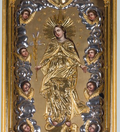 Zdjęcie nr 4: Ołtarz otrzymał formę drewnianej, przyściennej struktury architektonicznej ze zwieńczeniem o trójosiowym, jednokondygnacyjnym założeniu. Nastawa prezentuje się jako struktura polichromowana w odcieniach jasnej seledynowej zieleni, rozbielonego granatu oraz czerwieni. Partie ornamentów zostały wyzłocone. Drewniana mensa z portatylem wspiera się na prostopadłościennym stipesie ołtarzowym. Jego przód zdobią trzy czworoboczne płaszczyzny zbliżone do kwadratu ujęte profilowanymi, złoconymi listwami. W ich centrum umieszczono płaskorzeźbione, złocone czteroliście w diagonalnym układzie. Dwa w skrajnych płycinach utworzono ze stylizowanych liści akantu, natomiast środkowy przyjął formę geometryczno-roślinną. Retabulum ustawiono na wysokiej podstawie w kształcie nawiązującym do wydłużonego trapezu z wklęsłymi bokami, wspierającej się na krótszym boku. Podstawę zamyka u góry łamana, profilowana listwa. Jej lico artykułowane jest czterema zbliżonymi do kwadratu płycinami obramionymi złotymi, profilowanymi listwami. Ich środek zdobią takie same stylizowane, płaskorzeźbione i złocone czteroliście o diagonalnym układzie, wpisane w kwadrat. Na środku mensy, na tle podstawy, ustawiono czworoboczne tabernakulum w formie kapliczki z dwuspadowym dachem flankowanej dwiema sterczynami z pinaklami, wyrastającymi z wydłużonych prostopadłościennych, wąskich przypór. Drzwiczki tabernakulum zdobi motyw płaskorzeźbionego kielicha ze srebrzoną hostią wpisaną w stylizowaną ostrołukową arkadę z noskami. Na podstawie nastawy wspiera się niski cokół zamknięty u góry fryzem z rytmicznie rozmieszczonymi, niewielkimi, płaskorzeźbionymi i złoconymi czterolistnymi rozetkami. Z cokołu wyrastają trzy ostrołukowe arkady o profilowanych krawędziach, w górnych częściach z wpisaną arkaturą, ozdobione płaskorzeźbionymi, złoconymi czołgankami, zwieńczone pinaklami. Arkada środkowa jest wyższa od flankujących ją arkad bocznych. Zdobi ją po bokach płaskorzeźbione obramienie z motywem złoconej wici roślinno-ornamentalnej. Ostrołukowe zamknięcie arkady wypełniono ażurowym maswerkiem z motywem czteroliścia wpisanego w koło, ujętego dwoma trójliściami. Wszystkie trzy arkady flankują smukłe sterczyny wyrastające z prostopadłościennych, wąskich przypór ustawionych na niskich cokolikach. Sterczyny przechodzą w pinakle zwieńczone kwiatonami. Dekorują je płaskorzeźbione i złocone czołganki. W przypadku arkad bocznych pomiędzy cokolikami wprowadzono podłużne płyciny ze stylizowanymi maswerkami, natomiast w arkadzie centralnej umieszczono niewielkie, diagonalne czteroliście. W polu środkowej arkady prezentowany jest obraz Matki Boskiej Niepokalanie Poczętej w płaskorzeźbionej, złoconej, drewnianej sukience wotywnej, a na zasuwach wizerunek Przemienienia Pańskiego i św. Walentego. W arkadach bocznych retabulum ustawiono z lewej strony pełnoplastyczną, polichromowaną rzeźbę z masy gipsowej św. Józefa z Dzieciątkiem, a z prawej św. Antoniego Padewskiego, także z Dzieciątkiem Jezus. Zwieńczenie nastawy zostało również ukształtowane architektonicznie. Tworzą je trzy ażurowe kapliczki z pinaklami ustawione na osiach retabulum. W kapliczce środkowej umieszczono pełnoplastyczną, polichromowaną figurę św. Franciszka z Asyżu z masy gipsowej. 