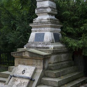 Zdjęcie nr 1: Nagrobek ustawiony na trójstopniowej podstawie i na cokole, w których na froncie mieści się wejście do grobu w formie przełamanego pod kątem leżącego prostokąta zamkniętego trójkątnym przyczółkiem z niszą, u spodu z reliefem: „GRÓB BAUMÓW”. Górna część nagrobka w kształcie dwustrefowego obelisku: dolna partia w formie ściętego ostrosłupa na profilowanym cokole, w polu trzech spośród czterech fakturowanych ścianek tablice, powyżej czworoboczny wałek dekorowany płaskorzeźbionymi gałązkami laurowymi przeplatanymi z wstęgą, strefa zakończona gzymsem. Górna część zwężająca się ku górze w postaci wklęsło-wypukłego profilowanego cokołu dźwigającego kostkę dekorowaną z czterech stron kaboszonami oraz sześcian. 
Płyta na południowej ściance bocznej: „ANTONI BARON BAUM / C(ESARSKO) K(RÓLEWSKI) RADCA DWORU / URODZONY 6 WRZEŚNIA 1763. / ZMARŁ 29 WRZEŚNIA 1829 R(OKU) / HELENA / BARONOWA BAUMOWA / ŻONA ANTONIEGO / *1797 + 1884.”. Płyta na ściance frontowej: „JÓZEF BARON BAUM / PREZES RADY POWIATOWEJ WADOWICKIEJ / POSEŁ NA SEJM KRAJOWY I DO RADY PAŃSTWA / WICE PREZES KOŁA POLSKIEGO W WIEDNIU / PREZES TOWARZYSTWA WZAJ(EMNYCH) UBEZP(IECZEŃ) W KRAKOWIE / I. T. D. / URODZONY 12. PAŹDŹ(IERNIKA) 1821 / ZMARŁ 11. MARCA 1883.” Płyta na północnej ściance bocznej: „WIKTOR JÓZEF B(A)R(ON) BAUM / URODZ(ONY) 23/10 1845 ZMARŁ 3/10 1846 / JÓZEFA B(A)R(ONOWA) BAUMÓWNA / URODZ(ONA) 4/4 1854 ZMARŁA 18/4 1854 R(OKU)”. Na cokole obelisku sygnatura: „E(DWARD) STEHLIK W KRAKOWIE”.