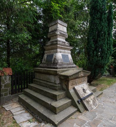 Zdjęcie nr 3: Nagrobek ustawiony na trójstopniowej podstawie i na cokole, w których na froncie mieści się wejście do grobu w formie przełamanego pod kątem leżącego prostokąta zamkniętego trójkątnym przyczółkiem z niszą, u spodu z reliefem: „GRÓB BAUMÓW”. Górna część nagrobka w kształcie dwustrefowego obelisku: dolna partia w formie ściętego ostrosłupa na profilowanym cokole, w polu trzech spośród czterech fakturowanych ścianek tablice, powyżej czworoboczny wałek dekorowany płaskorzeźbionymi gałązkami laurowymi przeplatanymi z wstęgą, strefa zakończona gzymsem. Górna część zwężająca się ku górze w postaci wklęsło-wypukłego profilowanego cokołu dźwigającego kostkę dekorowaną z czterech stron kaboszonami oraz sześcian. 
Płyta na południowej ściance bocznej: „ANTONI BARON BAUM / C(ESARSKO) K(RÓLEWSKI) RADCA DWORU / URODZONY 6 WRZEŚNIA 1763. / ZMARŁ 29 WRZEŚNIA 1829 R(OKU) / HELENA / BARONOWA BAUMOWA / ŻONA ANTONIEGO / *1797 + 1884.”. Płyta na ściance frontowej: „JÓZEF BARON BAUM / PREZES RADY POWIATOWEJ WADOWICKIEJ / POSEŁ NA SEJM KRAJOWY I DO RADY PAŃSTWA / WICE PREZES KOŁA POLSKIEGO W WIEDNIU / PREZES TOWARZYSTWA WZAJ(EMNYCH) UBEZP(IECZEŃ) W KRAKOWIE / I. T. D. / URODZONY 12. PAŹDŹ(IERNIKA) 1821 / ZMARŁ 11. MARCA 1883.” Płyta na północnej ściance bocznej: „WIKTOR JÓZEF B(A)R(ON) BAUM / URODZ(ONY) 23/10 1845 ZMARŁ 3/10 1846 / JÓZEFA B(A)R(ONOWA) BAUMÓWNA / URODZ(ONA) 4/4 1854 ZMARŁA 18/4 1854 R(OKU)”. Na cokole obelisku sygnatura: „E(DWARD) STEHLIK W KRAKOWIE”.