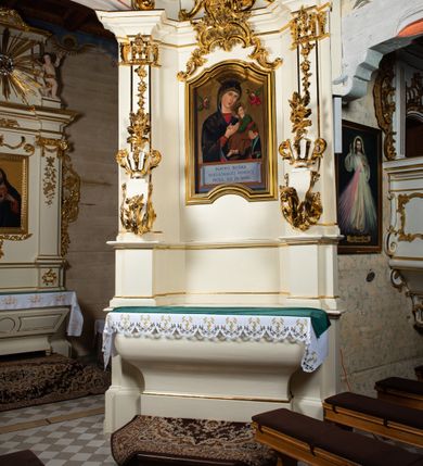 Zdjęcie nr 2: Ołtarz architektoniczny, jednokondygnacyjny, jednoosiowy ze zwieńczeniem. Ołtarz drewniany, sarkofagowy z drewnianą mensą. Retabulum ustawione na zdwojonym cokole o zryzalitowanych bokach. Kondygnacja ujęta jest  parą ustawionych ukośnie do wewnątrz, zdwojonych pilastrów z nałożoną w dolnej partii parą spływów wolutowych, wspierających przełamujący się ponad nimi, silnie wysunięty gzyms. Woluty spływów retabulum zdobione wydatnym rocaille'm oraz parą rokokowych wazonów z gałązkami różyczek. Pole środkowe retabulum w kształcie stojącego prostokąta ujętego dołem odcinkowym łukiem nadwieszonym, od góry zamknięte łukiem wklęsło-wypukłym z uskokami; w polu obraz Matki Nieustającej Pomocy. Trzony pilastrów zdobione podwieszonymi gałązkami z różyczkami, a kapitele ornamentem rocaille'owym. Górną partię środkowego pola retabulum ozdabia ornament rocaille'owy. Zwieńczenie ujęte jest spływami wolutowymi o skośnie ustawionych dolnych partiach, zamknięte odcinkiem gzymsu w kształcie łuku wklęsło-wypukłego. Szczyt zwieńczenia w formie ażurowej, rocaille'owej konchy. Pole środkowe o wklęsłych bokach, ściętych dolnych narożach, zamknięte łukiem wklęsło-wypukłym, ujęte profilowaną złoconą ramą; w środku obraz św. Walentego. Krawędzie spływów wolutowych zdobione parą gałązek palmowych. Struktura polichromowana na biało, cokół w kolorze jasnoszarym z żółtym profilowaniem; partie detalu architektonicznego i ornamentyki złocone i srebrzone.      

