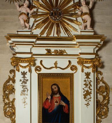 Zdjęcie nr 16: Ołtarz architektoniczny, jednokondygnacyjny, jednoosiowy ze zwieńczeniem. Mensa drewniana, sarkofagowa, ustawiona na parze nóżek w kształcie kul ujętych w górnej partii liśćmi laurowymi z kamiennym portatylem. Na ściance przedniej ozdobiona jest parą płycin w kształcie leżących prostokątów o wklęsłych bokach wewnętrznych; pomiędzy nimi płycina w kształcie koła ze złoconym napisem na niebieskim tle „ALTARE PRIVIL(EGIATUM)”. Retabulum ustawione jest na zdwojonym cokole o zryzalitowanych bokach. Nastawa ujęta parą zdwojonych pilastrów z kapitelami jońskimi, wspierających przełamujące się ponad nimi belkowanie. Pole środkowe retabulum w kształcie stojącego prostokąta, ujęte profilowaną i złoconą ramą z motywem wąskiej szarfy oplatającej cieniutki wałek; w polu obraz Najświętszego Serca Jezusa. Retabulum flankowane jest po bokach parą ażurowych uszaków w formie stylizowanej wici roślinnej z kwiatami. Górną partię trzonów pilastrów zdobi para festonów z liści laurowych, trzony dekorowane są grawerowanymi zwisami w formie gałązek z kwiatami i owocami. W dolnej i górnej partii pola środkowego retabulum ornamentyka rocaille’owa. Gzyms retabulum ozdabia jońska kostka. Zwieńczenie o wklęsłych bokach, ujęte parą wygiętych pilastrów na niewysokich cokołach, podtrzymujących wyłamujące się ponad nimi belkowanie. W polu głównym znajduje się promienista gloria z monogramem maryjnym pośrodku, otoczonym wieńcem z obłoków. Krawędzie boków zdobione są liściastymi gałązkami. Na gzymsie retabulum, po bokach ustawiona jest para aniołków. Struktura ołtarza polichromowana jest w odcieniach szarości, część dolna w kolorze ciemnoszarym, a górna w jasnoszarym; pola płycin antepedium malowane w odcieniach błękitów. Partie detalu architektonicznego i ornamentyka złocone i srebrzone. 
