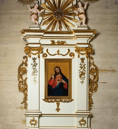 Zdjęcie nr 1: Ołtarz architektoniczny, jednokondygnacyjny, jednoosiowy ze zwieńczeniem. Mensa drewniana, sarkofagowa, ustawiona na parze nóżek w kształcie kul ujętych w górnej partii liśćmi laurowymi z kamiennym portatylem. Na ściance przedniej ozdobiona jest parą płycin w kształcie leżących prostokątów o wklęsłych bokach wewnętrznych; pomiędzy nimi płycina w kształcie koła ze złoconym napisem na niebieskim tle „ALTARE PRIVIL(EGIATUM)”. Retabulum ustawione jest na zdwojonym cokole o zryzalitowanych bokach. Nastawa ujęta parą zdwojonych pilastrów z kapitelami jońskimi, wspierających przełamujące się ponad nimi belkowanie. Pole środkowe retabulum w kształcie stojącego prostokąta, ujęte profilowaną i złoconą ramą z motywem wąskiej szarfy oplatającej cieniutki wałek; w polu obraz Najświętszego Serca Jezusa. Retabulum flankowane jest po bokach parą ażurowych uszaków w formie stylizowanej wici roślinnej z kwiatami. Górną partię trzonów pilastrów zdobi para festonów z liści laurowych, trzony dekorowane są grawerowanymi zwisami w formie gałązek z kwiatami i owocami. W dolnej i górnej partii pola środkowego retabulum ornamentyka rocaille’owa. Gzyms retabulum ozdabia jońska kostka. Zwieńczenie o wklęsłych bokach, ujęte parą wygiętych pilastrów na niewysokich cokołach, podtrzymujących wyłamujące się ponad nimi belkowanie. W polu głównym znajduje się promienista gloria z monogramem maryjnym pośrodku, otoczonym wieńcem z obłoków. Krawędzie boków zdobione są liściastymi gałązkami. Na gzymsie retabulum, po bokach ustawiona jest para aniołków. Struktura ołtarza polichromowana jest w odcieniach szarości, część dolna w kolorze ciemnoszarym, a górna w jasnoszarym; pola płycin antepedium malowane w odcieniach błękitów. Partie detalu architektonicznego i ornamentyka złocone i srebrzone. 
