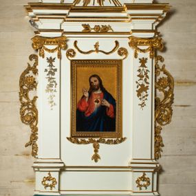 Zdjęcie nr 1: Ołtarz architektoniczny, jednokondygnacyjny, jednoosiowy ze zwieńczeniem. Mensa drewniana, sarkofagowa, ustawiona na parze nóżek w kształcie kul ujętych w górnej partii liśćmi laurowymi z kamiennym portatylem. Na ściance przedniej ozdobiona jest parą płycin w kształcie leżących prostokątów o wklęsłych bokach wewnętrznych; pomiędzy nimi płycina w kształcie koła ze złoconym napisem na niebieskim tle „ALTARE PRIVIL(EGIATUM)”. Retabulum ustawione jest na zdwojonym cokole o zryzalitowanych bokach. Nastawa ujęta parą zdwojonych pilastrów z kapitelami jońskimi, wspierających przełamujące się ponad nimi belkowanie. Pole środkowe retabulum w kształcie stojącego prostokąta, ujęte profilowaną i złoconą ramą z motywem wąskiej szarfy oplatającej cieniutki wałek; w polu obraz Najświętszego Serca Jezusa. Retabulum flankowane jest po bokach parą ażurowych uszaków w formie stylizowanej wici roślinnej z kwiatami. Górną partię trzonów pilastrów zdobi para festonów z liści laurowych, trzony dekorowane są grawerowanymi zwisami w formie gałązek z kwiatami i owocami. W dolnej i górnej partii pola środkowego retabulum ornamentyka rocaille’owa. Gzyms retabulum ozdabia jońska kostka. Zwieńczenie o wklęsłych bokach, ujęte parą wygiętych pilastrów na niewysokich cokołach, podtrzymujących wyłamujące się ponad nimi belkowanie. W polu głównym znajduje się promienista gloria z monogramem maryjnym pośrodku, otoczonym wieńcem z obłoków. Krawędzie boków zdobione są liściastymi gałązkami. Na gzymsie retabulum, po bokach ustawiona jest para aniołków. Struktura ołtarza polichromowana jest w odcieniach szarości, część dolna w kolorze ciemnoszarym, a górna w jasnoszarym; pola płycin antepedium malowane w odcieniach błękitów. Partie detalu architektonicznego i ornamentyka złocone i srebrzone. 
