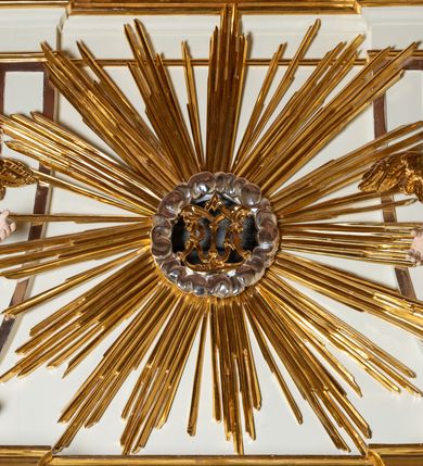 Zdjęcie nr 6: Ołtarz architektoniczny, jednokondygnacyjny, jednoosiowy ze zwieńczeniem. Mensa drewniana, sarkofagowa, ustawiona na parze nóżek w kształcie kul ujętych w górnej partii liśćmi laurowymi z kamiennym portatylem. Na ściance przedniej ozdobiona jest parą płycin w kształcie leżących prostokątów o wklęsłych bokach wewnętrznych; pomiędzy nimi płycina w kształcie koła ze złoconym napisem na niebieskim tle „ALTARE PRIVIL(EGIATUM)”. Retabulum ustawione jest na zdwojonym cokole o zryzalitowanych bokach. Nastawa ujęta parą zdwojonych pilastrów z kapitelami jońskimi, wspierających przełamujące się ponad nimi belkowanie. Pole środkowe retabulum w kształcie stojącego prostokąta, ujęte profilowaną i złoconą ramą z motywem wąskiej szarfy oplatającej cieniutki wałek; w polu obraz Najświętszego Serca Jezusa. Retabulum flankowane jest po bokach parą ażurowych uszaków w formie stylizowanej wici roślinnej z kwiatami. Górną partię trzonów pilastrów zdobi para festonów z liści laurowych, trzony dekorowane są grawerowanymi zwisami w formie gałązek z kwiatami i owocami. W dolnej i górnej partii pola środkowego retabulum ornamentyka rocaille’owa. Gzyms retabulum ozdabia jońska kostka. Zwieńczenie o wklęsłych bokach, ujęte parą wygiętych pilastrów na niewysokich cokołach, podtrzymujących wyłamujące się ponad nimi belkowanie. W polu głównym znajduje się promienista gloria z monogramem maryjnym pośrodku, otoczonym wieńcem z obłoków. Krawędzie boków zdobione są liściastymi gałązkami. Na gzymsie retabulum, po bokach ustawiona jest para aniołków. Struktura ołtarza polichromowana jest w odcieniach szarości, część dolna w kolorze ciemnoszarym, a górna w jasnoszarym; pola płycin antepedium malowane w odcieniach błękitów. Partie detalu architektonicznego i ornamentyka złocone i srebrzone. 
