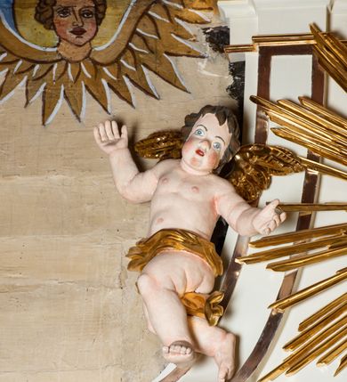 Zdjęcie nr 9: Ołtarz architektoniczny, jednokondygnacyjny, jednoosiowy ze zwieńczeniem. Mensa drewniana, sarkofagowa, ustawiona na parze nóżek w kształcie kul ujętych w górnej partii liśćmi laurowymi z kamiennym portatylem. Na ściance przedniej ozdobiona jest parą płycin w kształcie leżących prostokątów o wklęsłych bokach wewnętrznych; pomiędzy nimi płycina w kształcie koła ze złoconym napisem na niebieskim tle „ALTARE PRIVIL(EGIATUM)”. Retabulum ustawione jest na zdwojonym cokole o zryzalitowanych bokach. Nastawa ujęta parą zdwojonych pilastrów z kapitelami jońskimi, wspierających przełamujące się ponad nimi belkowanie. Pole środkowe retabulum w kształcie stojącego prostokąta, ujęte profilowaną i złoconą ramą z motywem wąskiej szarfy oplatającej cieniutki wałek; w polu obraz Najświętszego Serca Jezusa. Retabulum flankowane jest po bokach parą ażurowych uszaków w formie stylizowanej wici roślinnej z kwiatami. Górną partię trzonów pilastrów zdobi para festonów z liści laurowych, trzony dekorowane są grawerowanymi zwisami w formie gałązek z kwiatami i owocami. W dolnej i górnej partii pola środkowego retabulum ornamentyka rocaille’owa. Gzyms retabulum ozdabia jońska kostka. Zwieńczenie o wklęsłych bokach, ujęte parą wygiętych pilastrów na niewysokich cokołach, podtrzymujących wyłamujące się ponad nimi belkowanie. W polu głównym znajduje się promienista gloria z monogramem maryjnym pośrodku, otoczonym wieńcem z obłoków. Krawędzie boków zdobione są liściastymi gałązkami. Na gzymsie retabulum, po bokach ustawiona jest para aniołków. Struktura ołtarza polichromowana jest w odcieniach szarości, część dolna w kolorze ciemnoszarym, a górna w jasnoszarym; pola płycin antepedium malowane w odcieniach błękitów. Partie detalu architektonicznego i ornamentyka złocone i srebrzone. 
