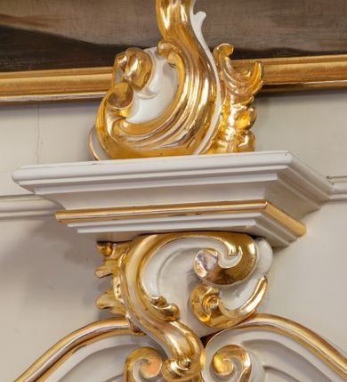 Zdjęcie nr 11: Nastawa ołtarzowa architektoniczna, trójosiowa, jednokondygnacyjna ze zwieńczeniem i bramkami. Ołtarz drewniany, prostopadłościenny; antepedium haftowane. Tabernakulum metalowe, fakturowane, w formie zbliżonej do prostopadłościennej skrzynki, ustawione na niskim cokole, o wypukłej ściance frontowej, flankowane parą kolumn o kompozytowych kapitelach. Drzwiczki w kształcie stojącego prostokąta, zamkniętego łukiem nadwieszonym; w polu kielich z hostią, a po bokach winna winorośl i kłosy zbóż. Powyżej jest tron wystawienia o fantazyjnym kształcie, ujęty po bokach wolutami, na których usadzone są dwa putta. W polu maska lunarna, otoczona promienistą glorią, a w zwieńczeniu muszla palmetowa. Nastawa ustawiona jest na wysokim, zdwojonym cokole, flankowana dwiema parami zdwojonych pilastrów, ustawionych ukośnie. Bramki w kształcie stojących prostokątów, zamkniętych półkoliście, w profilowanej obudowie zwieńczonej wolutowo. Drzwiczki dekorowane są malowanym bukietem kwiatów w wazonie. Kondygnacja o delikatnie wklęsłym przebiegu, ujęta dwiema parami zdwojonych, kanelowanych pilastrów, z których wewnętrzne ustawione są pod kątem. Podpory dźwigają pełne belkowanie, wyłamane nad osiami. Na linii wewnętrznych podpór ustawione są dwa cokoły, na których osadzono dwie główki aniołków, a na linii skrajnych podpór wolutowe przyczółki; z kolei pomiędzy nimi znajdują się fantazyjne woluty. W polu środkowym w ramie o kształcie stojącego prostokąta, zamkniętego łukiem wklęsło-wypukłym z uskokami umieszczony jest obraz Wniebowzięcia Najświętszej Marii Panny, a na zasuwie obraz św. Marcina oraz płótno przedstawiające Chrystusa Ukrzyżowanego. W osiach bocznych obrazy: po lewej św. Szczepan, a po prawej św. Wawrzyniec. Przed skrajnymi podporami ustawione są figury: po lewej św. Piotra, a po prawej św. Pawła. Nad polem głównym zawieszona jest gołębica Ducha Świętego na tle srebrzonych obłoków i promienistej glorii. Zwieńczenie w formie zbliżonej do leżącego prostokąta ujętego spływami wolutowymi, zamknięte profilowanym gzymsem i rocaille’ami. W polu obraz św. Marcina. Struktura polichromowana w kolorze jasnobeżowym, ornamentyka złocona, detale srebrzone.



