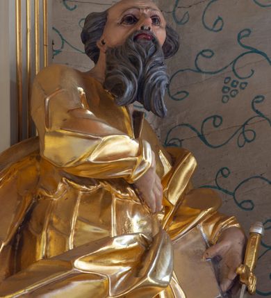 Zdjęcie nr 21: Nastawa ołtarzowa architektoniczna, trójosiowa, jednokondygnacyjna ze zwieńczeniem i bramkami. Ołtarz drewniany, prostopadłościenny; antepedium haftowane. Tabernakulum metalowe, fakturowane, w formie zbliżonej do prostopadłościennej skrzynki, ustawione na niskim cokole, o wypukłej ściance frontowej, flankowane parą kolumn o kompozytowych kapitelach. Drzwiczki w kształcie stojącego prostokąta, zamkniętego łukiem nadwieszonym; w polu kielich z hostią, a po bokach winna winorośl i kłosy zbóż. Powyżej jest tron wystawienia o fantazyjnym kształcie, ujęty po bokach wolutami, na których usadzone są dwa putta. W polu maska lunarna, otoczona promienistą glorią, a w zwieńczeniu muszla palmetowa. Nastawa ustawiona jest na wysokim, zdwojonym cokole, flankowana dwiema parami zdwojonych pilastrów, ustawionych ukośnie. Bramki w kształcie stojących prostokątów, zamkniętych półkoliście, w profilowanej obudowie zwieńczonej wolutowo. Drzwiczki dekorowane są malowanym bukietem kwiatów w wazonie. Kondygnacja o delikatnie wklęsłym przebiegu, ujęta dwiema parami zdwojonych, kanelowanych pilastrów, z których wewnętrzne ustawione są pod kątem. Podpory dźwigają pełne belkowanie, wyłamane nad osiami. Na linii wewnętrznych podpór ustawione są dwa cokoły, na których osadzono dwie główki aniołków, a na linii skrajnych podpór wolutowe przyczółki; z kolei pomiędzy nimi znajdują się fantazyjne woluty. W polu środkowym w ramie o kształcie stojącego prostokąta, zamkniętego łukiem wklęsło-wypukłym z uskokami umieszczony jest obraz Wniebowzięcia Najświętszej Marii Panny, a na zasuwie obraz św. Marcina oraz płótno przedstawiające Chrystusa Ukrzyżowanego. W osiach bocznych obrazy: po lewej św. Szczepan, a po prawej św. Wawrzyniec. Przed skrajnymi podporami ustawione są figury: po lewej św. Piotra, a po prawej św. Pawła. Nad polem głównym zawieszona jest gołębica Ducha Świętego na tle srebrzonych obłoków i promienistej glorii. Zwieńczenie w formie zbliżonej do leżącego prostokąta ujętego spływami wolutowymi, zamknięte profilowanym gzymsem i rocaille’ami. W polu obraz św. Marcina. Struktura polichromowana w kolorze jasnobeżowym, ornamentyka złocona, detale srebrzone.



