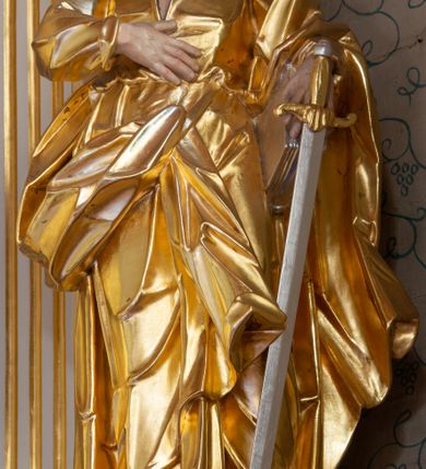 Zdjęcie nr 18: Nastawa ołtarzowa architektoniczna, trójosiowa, jednokondygnacyjna ze zwieńczeniem i bramkami. Ołtarz drewniany, prostopadłościenny; antepedium haftowane. Tabernakulum metalowe, fakturowane, w formie zbliżonej do prostopadłościennej skrzynki, ustawione na niskim cokole, o wypukłej ściance frontowej, flankowane parą kolumn o kompozytowych kapitelach. Drzwiczki w kształcie stojącego prostokąta, zamkniętego łukiem nadwieszonym; w polu kielich z hostią, a po bokach winna winorośl i kłosy zbóż. Powyżej jest tron wystawienia o fantazyjnym kształcie, ujęty po bokach wolutami, na których usadzone są dwa putta. W polu maska lunarna, otoczona promienistą glorią, a w zwieńczeniu muszla palmetowa. Nastawa ustawiona jest na wysokim, zdwojonym cokole, flankowana dwiema parami zdwojonych pilastrów, ustawionych ukośnie. Bramki w kształcie stojących prostokątów, zamkniętych półkoliście, w profilowanej obudowie zwieńczonej wolutowo. Drzwiczki dekorowane są malowanym bukietem kwiatów w wazonie. Kondygnacja o delikatnie wklęsłym przebiegu, ujęta dwiema parami zdwojonych, kanelowanych pilastrów, z których wewnętrzne ustawione są pod kątem. Podpory dźwigają pełne belkowanie, wyłamane nad osiami. Na linii wewnętrznych podpór ustawione są dwa cokoły, na których osadzono dwie główki aniołków, a na linii skrajnych podpór wolutowe przyczółki; z kolei pomiędzy nimi znajdują się fantazyjne woluty. W polu środkowym w ramie o kształcie stojącego prostokąta, zamkniętego łukiem wklęsło-wypukłym z uskokami umieszczony jest obraz Wniebowzięcia Najświętszej Marii Panny, a na zasuwie obraz św. Marcina oraz płótno przedstawiające Chrystusa Ukrzyżowanego. W osiach bocznych obrazy: po lewej św. Szczepan, a po prawej św. Wawrzyniec. Przed skrajnymi podporami ustawione są figury: po lewej św. Piotra, a po prawej św. Pawła. Nad polem głównym zawieszona jest gołębica Ducha Świętego na tle srebrzonych obłoków i promienistej glorii. Zwieńczenie w formie zbliżonej do leżącego prostokąta ujętego spływami wolutowymi, zamknięte profilowanym gzymsem i rocaille’ami. W polu obraz św. Marcina. Struktura polichromowana w kolorze jasnobeżowym, ornamentyka złocona, detale srebrzone.



