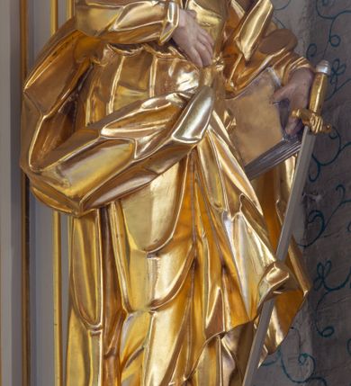 Zdjęcie nr 19: Nastawa ołtarzowa architektoniczna, trójosiowa, jednokondygnacyjna ze zwieńczeniem i bramkami. Ołtarz drewniany, prostopadłościenny; antepedium haftowane. Tabernakulum metalowe, fakturowane, w formie zbliżonej do prostopadłościennej skrzynki, ustawione na niskim cokole, o wypukłej ściance frontowej, flankowane parą kolumn o kompozytowych kapitelach. Drzwiczki w kształcie stojącego prostokąta, zamkniętego łukiem nadwieszonym; w polu kielich z hostią, a po bokach winna winorośl i kłosy zbóż. Powyżej jest tron wystawienia o fantazyjnym kształcie, ujęty po bokach wolutami, na których usadzone są dwa putta. W polu maska lunarna, otoczona promienistą glorią, a w zwieńczeniu muszla palmetowa. Nastawa ustawiona jest na wysokim, zdwojonym cokole, flankowana dwiema parami zdwojonych pilastrów, ustawionych ukośnie. Bramki w kształcie stojących prostokątów, zamkniętych półkoliście, w profilowanej obudowie zwieńczonej wolutowo. Drzwiczki dekorowane są malowanym bukietem kwiatów w wazonie. Kondygnacja o delikatnie wklęsłym przebiegu, ujęta dwiema parami zdwojonych, kanelowanych pilastrów, z których wewnętrzne ustawione są pod kątem. Podpory dźwigają pełne belkowanie, wyłamane nad osiami. Na linii wewnętrznych podpór ustawione są dwa cokoły, na których osadzono dwie główki aniołków, a na linii skrajnych podpór wolutowe przyczółki; z kolei pomiędzy nimi znajdują się fantazyjne woluty. W polu środkowym w ramie o kształcie stojącego prostokąta, zamkniętego łukiem wklęsło-wypukłym z uskokami umieszczony jest obraz Wniebowzięcia Najświętszej Marii Panny, a na zasuwie obraz św. Marcina oraz płótno przedstawiające Chrystusa Ukrzyżowanego. W osiach bocznych obrazy: po lewej św. Szczepan, a po prawej św. Wawrzyniec. Przed skrajnymi podporami ustawione są figury: po lewej św. Piotra, a po prawej św. Pawła. Nad polem głównym zawieszona jest gołębica Ducha Świętego na tle srebrzonych obłoków i promienistej glorii. Zwieńczenie w formie zbliżonej do leżącego prostokąta ujętego spływami wolutowymi, zamknięte profilowanym gzymsem i rocaille’ami. W polu obraz św. Marcina. Struktura polichromowana w kolorze jasnobeżowym, ornamentyka złocona, detale srebrzone.



