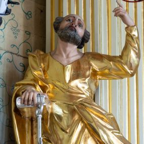 Zdjęcie nr 1: Rzeźba drążona, ustawiona na niskiej prostopadłościennej podstawie. Święty Piotr ukazany jest frontalnie w delikatnym kontrapoście z lewą ręką wzniesioną ku górze z wskazującym palcem, a prawą podtrzymującą na biodrze księgę i klucz. Twarz szczupła z wysokim czołem, z dużymi szeroko otwartymi oczami zwróconymi ku górze, nos duży; okolona krótką brodą oraz krótkimi silnie skręconymi włosami usytułowanymi po bokach głowy. Ubrany jest w długą tunikę o wąskich rękawach, ściśle przylegającą do ciała; tkanina obficie marszczona z grubymi, łamanymi fałdami w dolnej partii. Płaszcz zarzucony na prawe ramię, opadający wzdłuż prawego boku i zawinięty w pasie na lewym biodrze. Tkanina jest ekspresyjnie drapowana w grube łamane fałdy, o wywiniętym brzegu. Polichromia naturalistyczna w odsłoniętych partiach ciała, szaty złocone, atrybuty srebrzone.