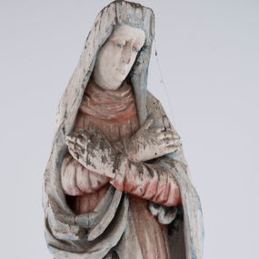 Zdjęcie nr 1: Pełnoplastyczna rzeźba Matki Boskiej Bolesnej ustawionej frontalnie, w lekkim kontrapoście, z prawą nogą ugiętą w kolanie i rękami skrzyżowanymi na piersi. Maria skręca głowę nieznacznie w lewo, spogląda smutno w dół. Na podłużnej twarzy odznaczają się wysokie czoło, duże, migdałowe, półprzymknięte oczy, wąski nos, niewielkie usta oraz szeroki podbródek. Ubrana jest w czerwoną suknię o wąskich, marszczących się równoległymi fałdami rękawach i kołnierzu, spływającą do ziemi podłużnymi fałdami. Na nią nałożony ma jasnoniebieski, zarzucony na głowę płaszcz, który zakrywa plecy i spływa na ramiona. Prawa poła przytrzymana między rękami zawija się przy prawym biodrze łamanymi fałdami. Spod sukni widoczne ciemnobrązowe, szpiczaste buty.