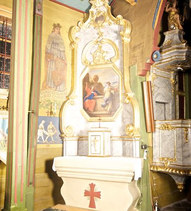 Zdjęcie nr 1: Ołtarz jednoosiowy, jednokondygnacyjny. Mensa w typie sarkofagowym, z krzyżem na ścianie frontowej. Na niej prostopadłościenne tabernakulum zamknięte od dołu i od góry gzymsem z krucyfiksem na drzwiczkach. Nastawa ołtarzowa na cokole o bokach dostawionych ukośnie, ujętych szerokimi taśmami o wolutowych zakończeniach i wspartymi na nich spływami. Górna część retabulum zwężająca się ku górze ujęta ceownicami i spływami wolutowymi o fantazyjnym kształcie. W polu nastawy obraz w kształcie stojącego prostokąta o ściętych narożach z przedstawieniem „Chrystusa z Samarytanką przy studni”. Powyżej obrazu dekoracja utworzona z dwóch karbowanych ceownic flankujących motyw koguciego grzebienia. Struktura marmoryzowana w odcieniach koloru szarego, profile i dekoracje złocone.