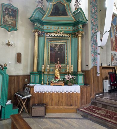 Zdjęcie nr 2: Ołtarz architektoniczny, jednoosiowy, jednokondygnacyjny ze zwieńczeniem. Nastawa na trójdzielnym cokole o uskokowych, skośnie ustawionych bokach. Retabulum ujęte parą kolumn korynckich z kanelurowanymi w dwóch trzecich wysokości trzonami, na tle zdwojonych pilastrów, wspierających wyłamujące się ponad nimi belkowanie z silnie wysuniętym gzymsem. W polu centralnym przedstawienie św. Antoniego Padewskiego w ramie w kształcie stojącego prostokąta zdobionej motywem liści laurowych. Powyżej wnęka ujęta lekko wypukłym lambrekinem z ażurowym szczytem i monogramem maryjnym pośrodku. Zwieńczenie o wklęsłych bokach, zamknięte odcinkiem gzymsu w kształcie łuku nadwieszonego, flankowane parą odcinków wklęsło-wypukłego naczółka, na których para przyklękających na jednym kolanie aniołków. W zwieńczeniu przedstawienie stygmatyzacji św. Franciszka ujęte profilowaną, złoconą ramą z motywami rocaille&#039;u w górnej partii. Dolna partia pola retabulum oraz fryz zdobione rozetami. Szczyt zwieńczenia w formie promienistej glorii z monogramem Chrystusa, flankowany parą wazonów płomienistych. 
Struktura polichromowana w odcieniach zieleni. Detal architektoniczny i ornamentyka złocone i srebrzone. 