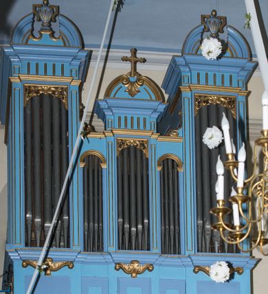 Zdjęcie nr 1: Organy architektoniczne, jednokondygnacyjne, pięcioosiowe na wysokim cokole zdobionym płycinami. Pola kondygnacji wypełnione piszczałkami, w osiach środkowej i bocznych zamknięte prostokątnie z ażurową dekoracją z wici roślinnej w górnej części, pozostałe zamknięte półkoliście. Wyróżnione dekoracją osie są wyższe od pozostałych, podtrzymują kawałki belkowania o silnie wysuniętym gzymsie i mają półkoliste zwieńczenia. Boczne przerwane na środku postumentami z wazonami, środkowe z  dekoracją z wolut i akantu oraz zatkniętym na szczycie krzyżem. 
Struktura polichromowana w kolorze niebieskim; ornamentyka i profile złocone.