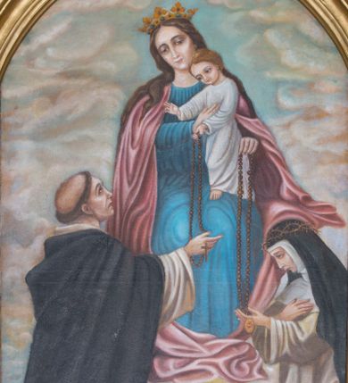 Zdjęcie nr 2: Obraz z przedstawieniem tronującej Matki Boskiej z Dzieciątkiem, przekazujących różańce klęczącym przed nimi 
 – św. Dominikowi i św. Katarzynie Sieneńskiej. Maria siedzi, spogląda delikatnie w dół. Na jej lewym kolanie stoi Dzieciątko, które podtrzymuje prawą ręką, lewą przekazując różaniec świętej. Maria ma trójkątną twarz z ciemnymi, otoczonymi cieniami oczami, wąskim nosem oraz małymi ustami. Jest ubrana w niebieską suknię oraz różowy, opadający drobnymi kaskadami na boki płaszcz, który fałduje się obficie pod jej stopami. Na głowie ma zdobioną drogimi kamieniami koronę. Dzieciątko spogląda na św. Dominika, prawą rękę wyciąga w jego kierunku w geście błogosławieństwa, lewą podaje mu różaniec. Ma okrągłą twarz, ciemne oczy, mały nos i usta, nieznacznie się uśmiecha. Jest ubrane w białą, długą sukienkę. Po lewej stronie przedstawienia klęczy św. Dominik, który spogląda na Dzieciątko i prawą ręką odbiera od niego różaniec. Ubrany jest w biały habit i czarny płaszcz zakonny, na głowie ma wyciętą tonsurę. Klęcząca po prawej stronie św. Katarzyna patrzy na podtrzymywany lewą ręką różaniec, prawą składa na piersi. Ubrana jest w biały habit i czarny płaszcz, na głowie ma koronę cierniową. Scena rozgrywa się na tle niebieskiego nieba przykrytego gęsto żółtopomarańczowymi chmurami. Między klęczącymi świętymi wyrasta z ziemi kwitnący krzew różany.