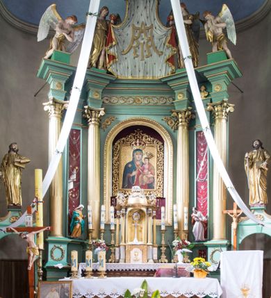 Zdjęcie nr 1: Ołtarz architektoniczny, przyścienny, jednokondygnacyjny ze zwieńczeniem i bramkami, ustawiony na dwóch stopniach. 
Na mensie tabernakulum i znajdujący się nad nim tron wystawienia na rzucie kwadratu o ściętych ćwierćkoliście narożach. Całość ujęta usadowionymi na wysokich cokołach kolumienkami dźwigającymi odcinki belkowania ze wspólnym gzymsem będące jednocześnie podstawami dla figur klęczących i stojących aniołów. W wieńczeniu półsferyczna kopuła dekorowana girlandami kwiatowymi zwieńczona księgą z siedmioma pieczęciami, na której leży baranek. 
Nastawa ołtarzowa architektoniczna, przyścienna, jednokondygnacyjna ze zwieńczeniem, jednoosiowa z bramkami, na dwustrefowym cokole. Ujęta dwiema parami kolumn o kanelowanych na wysokości dwóch trzecich trzonach i kapitelach kompozytowych, rozdzielonych półfilarami z gablotami wypełnionymi wotami, podtrzymującymi wyłamane na ich osi belkowanie. W polu środkowym nisza w formie stojącego prostokąta zamkniętego łukiem półkolistym mieszcząca obraz Matki Boskiej Śnieżnej. Zwieńczenie w formie trzymanego przez dwa anioły baldachimu z podwieszonym płaszczem królewskim z podbiciem gronostajowym i złotą lamówką, z gzymsem z podwieszonymi lambrekinami. Na płaszczu umieszczono monogram Marii. Na skraju belkowania para klęczących na podstawie aniołów. Bramki w formie arkad z kluczem, zwieńczone dwoma spływami wolutowymi stanowiącymi podstawę dla cokołów na figury św. Piotra i św. Pawła. Na cokołach kolumn wieńce laurowe, w partii fryzu rozety i przeplatająca się wić roślinna, w pachach rozety z wicią roślinną. Struktura polichromowana w kolorze seledynowym; kolumny, profile i ornamentyka złocone i srebrzone, anioły polichromowane naturalistycznie. 