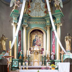 Zdjęcie nr 1: Ołtarz architektoniczny, przyścienny, jednokondygnacyjny ze zwieńczeniem i bramkami, ustawiony na dwóch stopniach. 
Na mensie tabernakulum i znajdujący się nad nim tron wystawienia na rzucie kwadratu o ściętych ćwierćkoliście narożach. Całość ujęta usadowionymi na wysokich cokołach kolumienkami dźwigającymi odcinki belkowania ze wspólnym gzymsem będące jednocześnie podstawami dla figur klęczących i stojących aniołów. W wieńczeniu półsferyczna kopuła dekorowana girlandami kwiatowymi zwieńczona księgą z siedmioma pieczęciami, na której leży baranek. 
Nastawa ołtarzowa architektoniczna, przyścienna, jednokondygnacyjna ze zwieńczeniem, jednoosiowa z bramkami, na dwustrefowym cokole. Ujęta dwiema parami kolumn o kanelowanych na wysokości dwóch trzecich trzonach i kapitelach kompozytowych, rozdzielonych półfilarami z gablotami wypełnionymi wotami, podtrzymującymi wyłamane na ich osi belkowanie. W polu środkowym nisza w formie stojącego prostokąta zamkniętego łukiem półkolistym mieszcząca obraz Matki Boskiej Śnieżnej. Zwieńczenie w formie trzymanego przez dwa anioły baldachimu z podwieszonym płaszczem królewskim z podbiciem gronostajowym i złotą lamówką, z gzymsem z podwieszonymi lambrekinami. Na płaszczu umieszczono monogram Marii. Na skraju belkowania para klęczących na podstawie aniołów. Bramki w formie arkad z kluczem, zwieńczone dwoma spływami wolutowymi stanowiącymi podstawę dla cokołów na figury św. Piotra i św. Pawła. Na cokołach kolumn wieńce laurowe, w partii fryzu rozety i przeplatająca się wić roślinna, w pachach rozety z wicią roślinną. Struktura polichromowana w kolorze seledynowym; kolumny, profile i ornamentyka złocone i srebrzone, anioły polichromowane naturalistycznie. 