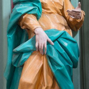 Zdjęcie nr 1: Rzeźba pełna, ustawiona na niewielkim cokole. Figura ukazana w całej postaci, zwrócona w trzech czwartych w lewo, w silnym kontrapoście, o esowato wygiętej sylwetce. Głowa delikatnie pochylona, skierowana w lewo; lewa ręka ugięta i uniesiona, prawa opuszczona z przodu, podtrzymuje płaszcz. Twarz szczupła, o wyraźnie zaznaczonej linii brody i kości policzkowych, oczy duże, płytko rzeźbione, nos niewielki. Święta jest ubrana w sięgającą ziemi,  żółtą suknię, przepasaną w talii, z wąskimi rękawami oraz dużym dekoltem z wywiniętą partią draperii przy brzegu. Tkanina przylega do ciała, jest marszczona w partii torsu i drapowana dołem w grube, pojedyncze fałdy. Turkusowy płaszcz przerzucony przez prawe przedramię opada przez plecy na lewy bok, z podtrzymywaną z przodu partią tkaniny, draperia silnie fałdowana. Na głowie długi, biały welon opadający na plecy. Polichromia naturalistyczna.
