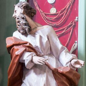 Zdjęcie nr 1: Rzeźba pełna, posadowiona na niskim cokole. Święty ukazany całopostaciowo, zwrócony w prawo, w silnym kontrapoście z prawą nogą odsuniętą do tyłu, z głową ukazaną z profilu, skierowaną w prawo. Obie ręce zwrócone w lewą stronę. Twarz szczupła, pociągła, o wydatnym, wąskim nosie i płytkich oczodołach, okolona długą gęstą brodą i krótkimi układającymi się w pukle włosami jakby rozwianymi do tyłu. Postać jest ubrana w jasną suknię sięgającą stóp, o dużym dekolcie odsłaniającym ramiona. Tkanina przylega do ciała, drapowana jest w grube, pojedyncze fałdy. Okrywający plecy brązowy płaszcz przerzucony przez prawe ramię i lewe biodro jest spięty taśmą na przodzie. Polichromia naturalistyczna.