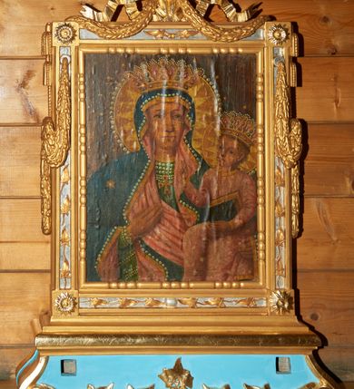 Zdjęcie nr 2: Feretron z obrazami Matki Boskiej z Dzieciątkiem oraz św. Klemensa, osadzony na podstawie w formie cokołu ujętego w narożach wolutami, dekorowanego wzdłuż dolnego brzegu liśćmi palmowymi. Cokół zaopatrzony jest w kwadratowe otwory na drążki do noszenia. Obrazy ujęte są ramą w formie stojącego prostokąta, dekorowaną w narożach rozetami; na czterech bokach srebrzone płyciny zdobione są ornamentem z liści, górny bok zwieńczony karbowaną wstęgą, od której spływają na boki feretronu festony. Z górnych krawędzi zwisają także dwie pary chwostów. Od wewnątrz rama dekorowana jest motywem skręconego sznura o geometrycznym przebiegu. 

Po jednej stronie feretronu znajduje się obraz Matki Boskiej z Dzieciątkiem. Maria ukazana jest frontalnie, w półpostaci. Na lewej ręce trzyma Dzieciątko Jezus, a prawą dłoń składa na piersi. Twarz podłużna z długim nosem i dużymi oczami, na prawym policzku dwie ukośnie biegnące rany. Maria ubrana jest w zieloną suknię z krzyżykiem na piersiach oraz ciemnozielony płaszcz założony na głowę z różową podszewką, złotą lamówką, dekorowany na brzegu białymi perełkami. Na prawym ramieniu Matka Boska ma złotą gwiazdę. Dzieciątko zwrócone jest trzy czwarte w prawo, w lewej dłoni trzyma księgę, a prawą czyni gest błogosławieństwa. Twarz ma trójkątną o wyrazistych rysach z dużymi oczami. Włosy w kolorze ciemnego blondu, kręcone i krótkie. Jezus ubrany jest w różową sukienkę z wąskimi rękawami, zdobioną białymi gwiazdkami i dekoracyjnym, złoconym wykończeniem pod szyją i na rękawach. Na głowie Marii i Dzieciątka znajdują się otwarte korony, bogato zdobione kamieniami szlachetnymi, a wokół głowy koliste nimby, wypełnione trójkątnymi promieniami i otoczone białymi perełkami. Tło jednolite, ciemne. 

Po drugiej stronie feretronu ukazany jest wizerunek św. Klemensa, w półpostaci, zwróconego delikatnie w lewo. Święty trzyma w prawej dłoni ferulę opartą o prawe ramię, a lewą rękę składa na piersi, zatykając kciuk za guzik sutanny. Twarz o rysach starszego mężczyzny z długą, siwą i bujną brodą, długim nosem i dużymi oczami. Święty ubrany jest w czerwoną sutannę z czerwonym mucetem, na szyi ma założoną białą stułę zdobioną złotymi motywami: krzyżem, infułą, skrzyżowanymi kluczami, skrzyżowanymi ferulą i krzyżem; na głowie ma założoną czerwoną piuskę. Święty Klemens prawą rękę opiera na otwartej księdze. Po prawej stronie obrazu stoi wysoka niebieska tiara ze złotymi koronami, a za nią ustawiony jest krucyfiks z figurą Chrystusa zwróconą w stronę świętego. Tło obrazu jest ciemne, brązowe. 

Cokół feretronu polichromowany jest na kolor jasnoniebieski, ornamentyka oraz detale złocone i srebrzone.

