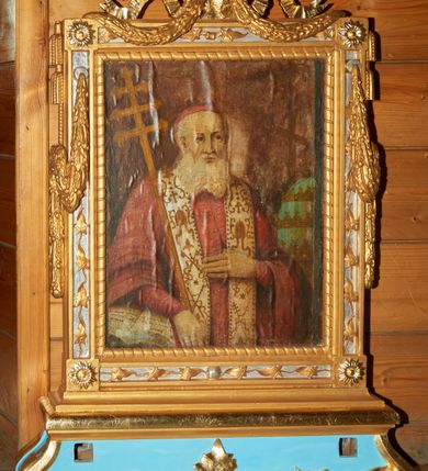 Zdjęcie nr 1: Feretron z obrazami Matki Boskiej z Dzieciątkiem oraz św. Klemensa, osadzony na podstawie w formie cokołu ujętego w narożach wolutami, dekorowanego wzdłuż dolnego brzegu liśćmi palmowymi. Cokół zaopatrzony jest w kwadratowe otwory na drążki do noszenia. Obrazy ujęte są ramą w formie stojącego prostokąta, dekorowaną w narożach rozetami; na czterech bokach srebrzone płyciny zdobione są ornamentem z liści, górny bok zwieńczony karbowaną wstęgą, od której spływają na boki feretronu festony. Z górnych krawędzi zwisają także dwie pary chwostów. Od wewnątrz rama dekorowana jest motywem skręconego sznura o geometrycznym przebiegu. 

Po jednej stronie feretronu znajduje się obraz Matki Boskiej z Dzieciątkiem. Maria ukazana jest frontalnie, w półpostaci. Na lewej ręce trzyma Dzieciątko Jezus, a prawą dłoń składa na piersi. Twarz podłużna z długim nosem i dużymi oczami, na prawym policzku dwie ukośnie biegnące rany. Maria ubrana jest w zieloną suknię z krzyżykiem na piersiach oraz ciemnozielony płaszcz założony na głowę z różową podszewką, złotą lamówką, dekorowany na brzegu białymi perełkami. Na prawym ramieniu Matka Boska ma złotą gwiazdę. Dzieciątko zwrócone jest trzy czwarte w prawo, w lewej dłoni trzyma księgę, a prawą czyni gest błogosławieństwa. Twarz ma trójkątną o wyrazistych rysach z dużymi oczami. Włosy w kolorze ciemnego blondu, kręcone i krótkie. Jezus ubrany jest w różową sukienkę z wąskimi rękawami, zdobioną białymi gwiazdkami i dekoracyjnym, złoconym wykończeniem pod szyją i na rękawach. Na głowie Marii i Dzieciątka znajdują się otwarte korony, bogato zdobione kamieniami szlachetnymi, a wokół głowy koliste nimby, wypełnione trójkątnymi promieniami i otoczone białymi perełkami. Tło jednolite, ciemne. 

Po drugiej stronie feretronu ukazany jest wizerunek św. Klemensa, w półpostaci, zwróconego delikatnie w lewo. Święty trzyma w prawej dłoni ferulę opartą o prawe ramię, a lewą rękę składa na piersi, zatykając kciuk za guzik sutanny. Twarz o rysach starszego mężczyzny z długą, siwą i bujną brodą, długim nosem i dużymi oczami. Święty ubrany jest w czerwoną sutannę z czerwonym mucetem, na szyi ma założoną białą stułę zdobioną złotymi motywami: krzyżem, infułą, skrzyżowanymi kluczami, skrzyżowanymi ferulą i krzyżem; na głowie ma założoną czerwoną piuskę. Święty Klemens prawą rękę opiera na otwartej księdze. Po prawej stronie obrazu stoi wysoka niebieska tiara ze złotymi koronami, a za nią ustawiony jest krucyfiks z figurą Chrystusa zwróconą w stronę świętego. Tło obrazu jest ciemne, brązowe. 

Cokół feretronu polichromowany jest na kolor jasnoniebieski, ornamentyka oraz detale złocone i srebrzone.

