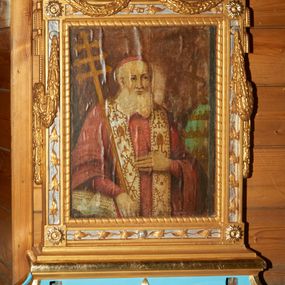 Zdjęcie nr 1: Feretron z obrazami Matki Boskiej z Dzieciątkiem oraz św. Klemensa, osadzony na podstawie w formie cokołu ujętego w narożach wolutami, dekorowanego wzdłuż dolnego brzegu liśćmi palmowymi. Cokół zaopatrzony jest w kwadratowe otwory na drążki do noszenia. Obrazy ujęte są ramą w formie stojącego prostokąta, dekorowaną w narożach rozetami; na czterech bokach srebrzone płyciny zdobione są ornamentem z liści, górny bok zwieńczony karbowaną wstęgą, od której spływają na boki feretronu festony. Z górnych krawędzi zwisają także dwie pary chwostów. Od wewnątrz rama dekorowana jest motywem skręconego sznura o geometrycznym przebiegu. 

Po jednej stronie feretronu znajduje się obraz Matki Boskiej z Dzieciątkiem. Maria ukazana jest frontalnie, w półpostaci. Na lewej ręce trzyma Dzieciątko Jezus, a prawą dłoń składa na piersi. Twarz podłużna z długim nosem i dużymi oczami, na prawym policzku dwie ukośnie biegnące rany. Maria ubrana jest w zieloną suknię z krzyżykiem na piersiach oraz ciemnozielony płaszcz założony na głowę z różową podszewką, złotą lamówką, dekorowany na brzegu białymi perełkami. Na prawym ramieniu Matka Boska ma złotą gwiazdę. Dzieciątko zwrócone jest trzy czwarte w prawo, w lewej dłoni trzyma księgę, a prawą czyni gest błogosławieństwa. Twarz ma trójkątną o wyrazistych rysach z dużymi oczami. Włosy w kolorze ciemnego blondu, kręcone i krótkie. Jezus ubrany jest w różową sukienkę z wąskimi rękawami, zdobioną białymi gwiazdkami i dekoracyjnym, złoconym wykończeniem pod szyją i na rękawach. Na głowie Marii i Dzieciątka znajdują się otwarte korony, bogato zdobione kamieniami szlachetnymi, a wokół głowy koliste nimby, wypełnione trójkątnymi promieniami i otoczone białymi perełkami. Tło jednolite, ciemne. 

Po drugiej stronie feretronu ukazany jest wizerunek św. Klemensa, w półpostaci, zwróconego delikatnie w lewo. Święty trzyma w prawej dłoni ferulę opartą o prawe ramię, a lewą rękę składa na piersi, zatykając kciuk za guzik sutanny. Twarz o rysach starszego mężczyzny z długą, siwą i bujną brodą, długim nosem i dużymi oczami. Święty ubrany jest w czerwoną sutannę z czerwonym mucetem, na szyi ma założoną białą stułę zdobioną złotymi motywami: krzyżem, infułą, skrzyżowanymi kluczami, skrzyżowanymi ferulą i krzyżem; na głowie ma założoną czerwoną piuskę. Święty Klemens prawą rękę opiera na otwartej księdze. Po prawej stronie obrazu stoi wysoka niebieska tiara ze złotymi koronami, a za nią ustawiony jest krucyfiks z figurą Chrystusa zwróconą w stronę świętego. Tło obrazu jest ciemne, brązowe. 

Cokół feretronu polichromowany jest na kolor jasnoniebieski, ornamentyka oraz detale złocone i srebrzone.

