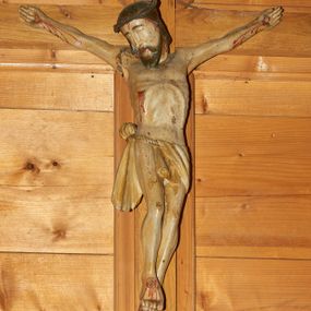 Zdjęcie nr 1: Rzeźba Chrystusa przybita do krzyża trzema gwoździami. Chrystus został ukazany w typie Cristo morto, w delikatnym zwisie, z głową skłonioną na prawe ramię, stopami założonymi prawa na lewą. Biodra ma przewiązane perizonium wiszącym na pojedynczym sznurze, przełożonym przez niego z lewej strony oraz zawiązanym na guza z prawej ze zwisem z prawej strony. Chrystus ma podłużną twarz, z wąskim nosem, zamkniętymi oczami, okoloną krótką i ciemnobrązową brodą; włosy długie i ciemnobrązowe, spływające na plecy. Na głowie ma założoną cienką koronę cierniową, splecioną z dwóch gałązek. Jego ciało jest szczupłe, o wyraźnie podkreślonej linii żeber i mostka, głęboko wciętej talii. Z ran spływają strużki krwi. Krzyż prosty, gładki, nad głową Chrytusa wisi titulus w formie poziomej banderoli z napisem „INRI”.


 