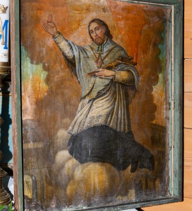 Zdjęcie nr 3: Obraz w kształcie stojącego prostokąta z przedstawieniem św. Jana Nepomucena ukazanego na tle obłoków. Święty ukazany w pozycji klęczącej, zwrócony trzy czwarte w prawą stronę z głową lekko pochyloną na prawy bok. W prawej uniesionej wysoko dłoni trzyma odcięty język, a w ugiętej lewej ręce podtrzymuje krucyfiks. Twarz owalna, okolona jasnymi włosami i krótkim zarostem, oczy skierowane ku górze, nos prosty, usta pełne. Święty ubrany jest w czarną sutannę, białą rokietę z długimi i wąskimi rękawami oraz jasnoniebieską almucję, u szyi ma niebiesko-białą befkę. Na szyi ma zawieszony na czerwonym sznurze wizerunek Matki Boskiej z Dzieciątkiem. Wokół głowy świętego znajduje się wieniec z pięciu gwiazd. W dolnej części obrazu po lewej stronie widoczne fragmenty architektury z półkolistą arkadą, a po prawej stronie zielony pejzaż. W górnej części pochmurne niebo z szerokim snopem światła padającym na świętego. 