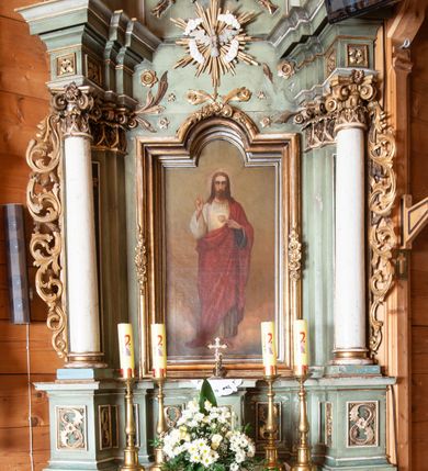 Zdjęcie nr 2: Ołtarz o strukturze architektonicznej, jednoosiowy, jednokondygnacyjny ze zwieńczeniem. Mensa ołtarzowa składająca się z wysokiego cokołu i skrzyni o bokach lekko zwężających się ku dołowi. Antepedium  w formie poziomej płyciny zwężającej się ku dołowi, spiętej stylizowanymi liśćmi w narożach. Wewnątrz zatarty, złoty napis. Tabernakulum wmontowane w partię cokołu, delikatnie wysunięte do przodu, ustawione na niskim cokole i zamknięte profilowanym gzymsem. Nastawa ołtarzowa ustawiona na cokole, flankowana parą zdwojonych pilastrów i ustawionymi przed nimi kolumnami podtrzymującymi pełne, przerwane nad polem głównym belkowanie oraz wolutowy, przerywany przyczółek. Cokół nastawy zdobiony płycinami, wewnątrz których roślinny ornament. Pilastry ozdobione prostokątną płyciną, w polu której znajduje się dekoracja roślinna. Kolumny ustawione na bazach, trzony polichromowane na biało, kapitele kompozytowe, stylizowane. W polu środkowym duża wnęka, ujęta ramą w kształcie stojącego prostokąta zamkniętego łukiem nadwieszonym z obrazem Najświętszego Serca Pana Jezusa.  Nad obrazem, w części przerwanego belkowania umieszczona rzeźbiona gołębica Ducha Świętego na tle promienistej glorii i obłoków. Kondygnacja ujęta uszami ze stylizowanego akantu, przeplecionego karbowaną wstęgą. 

Zwieńczenie w kształcie przypominającym stojący prostokąt o wklęsłych bokach, ujętych spływami wolutowymi oraz zamknięty falistym gzymsem utworzonym z dwóch wolut spiętych stylizowaną muszlą. Szczyt zwieńczenia i górne naroża ozdobione rzeźbionymi kwiatami. W polu obraz Ecce Homo w kształcie stojącego prostokąta o wklęsłych bokach i wklęsłych dolnych narożach, zamknięty u góry łukiem nadwieszonym. Rama po bokach spięta stylizowanymi liśćmi. Struktura polichromowana na kolor jasnozielony, kolumny na biało, snycerka złocona.

