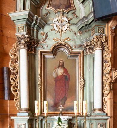 Zdjęcie nr 1: Ołtarz o strukturze architektonicznej, jednoosiowy, jednokondygnacyjny ze zwieńczeniem. Mensa ołtarzowa składająca się z wysokiego cokołu i skrzyni o bokach lekko zwężających się ku dołowi. Antepedium  w formie poziomej płyciny zwężającej się ku dołowi, spiętej stylizowanymi liśćmi w narożach. Wewnątrz zatarty, złoty napis. Tabernakulum wmontowane w partię cokołu, delikatnie wysunięte do przodu, ustawione na niskim cokole i zamknięte profilowanym gzymsem. Nastawa ołtarzowa ustawiona na cokole, flankowana parą zdwojonych pilastrów i ustawionymi przed nimi kolumnami podtrzymującymi pełne, przerwane nad polem głównym belkowanie oraz wolutowy, przerywany przyczółek. Cokół nastawy zdobiony płycinami, wewnątrz których roślinny ornament. Pilastry ozdobione prostokątną płyciną, w polu której znajduje się dekoracja roślinna. Kolumny ustawione na bazach, trzony polichromowane na biało, kapitele kompozytowe, stylizowane. W polu środkowym duża wnęka, ujęta ramą w kształcie stojącego prostokąta zamkniętego łukiem nadwieszonym z obrazem Najświętszego Serca Pana Jezusa.  Nad obrazem, w części przerwanego belkowania umieszczona rzeźbiona gołębica Ducha Świętego na tle promienistej glorii i obłoków. Kondygnacja ujęta uszami ze stylizowanego akantu, przeplecionego karbowaną wstęgą. 

Zwieńczenie w kształcie przypominającym stojący prostokąt o wklęsłych bokach, ujętych spływami wolutowymi oraz zamknięty falistym gzymsem utworzonym z dwóch wolut spiętych stylizowaną muszlą. Szczyt zwieńczenia i górne naroża ozdobione rzeźbionymi kwiatami. W polu obraz Ecce Homo w kształcie stojącego prostokąta o wklęsłych bokach i wklęsłych dolnych narożach, zamknięty u góry łukiem nadwieszonym. Rama po bokach spięta stylizowanymi liśćmi. Struktura polichromowana na kolor jasnozielony, kolumny na biało, snycerka złocona.

