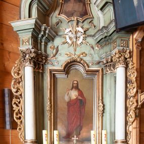 Zdjęcie nr 1: Ołtarz o strukturze architektonicznej, jednoosiowy, jednokondygnacyjny ze zwieńczeniem. Mensa ołtarzowa składająca się z wysokiego cokołu i skrzyni o bokach lekko zwężających się ku dołowi. Antepedium  w formie poziomej płyciny zwężającej się ku dołowi, spiętej stylizowanymi liśćmi w narożach. Wewnątrz zatarty, złoty napis. Tabernakulum wmontowane w partię cokołu, delikatnie wysunięte do przodu, ustawione na niskim cokole i zamknięte profilowanym gzymsem. Nastawa ołtarzowa ustawiona na cokole, flankowana parą zdwojonych pilastrów i ustawionymi przed nimi kolumnami podtrzymującymi pełne, przerwane nad polem głównym belkowanie oraz wolutowy, przerywany przyczółek. Cokół nastawy zdobiony płycinami, wewnątrz których roślinny ornament. Pilastry ozdobione prostokątną płyciną, w polu której znajduje się dekoracja roślinna. Kolumny ustawione na bazach, trzony polichromowane na biało, kapitele kompozytowe, stylizowane. W polu środkowym duża wnęka, ujęta ramą w kształcie stojącego prostokąta zamkniętego łukiem nadwieszonym z obrazem Najświętszego Serca Pana Jezusa.  Nad obrazem, w części przerwanego belkowania umieszczona rzeźbiona gołębica Ducha Świętego na tle promienistej glorii i obłoków. Kondygnacja ujęta uszami ze stylizowanego akantu, przeplecionego karbowaną wstęgą. 

Zwieńczenie w kształcie przypominającym stojący prostokąt o wklęsłych bokach, ujętych spływami wolutowymi oraz zamknięty falistym gzymsem utworzonym z dwóch wolut spiętych stylizowaną muszlą. Szczyt zwieńczenia i górne naroża ozdobione rzeźbionymi kwiatami. W polu obraz Ecce Homo w kształcie stojącego prostokąta o wklęsłych bokach i wklęsłych dolnych narożach, zamknięty u góry łukiem nadwieszonym. Rama po bokach spięta stylizowanymi liśćmi. Struktura polichromowana na kolor jasnozielony, kolumny na biało, snycerka złocona.

