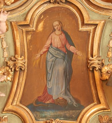 Zdjęcie nr 1: Obraz w kształcie stojącego prostokąta, umieszczony w ramie o potrójnie wklęsłej podstawie, wklęsłych bokach, zamkniętej łukiem nadwieszonym. W centrum kompozycji ukazana jest Matka Boska, frontalnie, stojąca na globie ziemskim, stopami depcząca węża. Lewa noga Marii ugięta w kolanie, oparta na głowie węża, ręce rozłożone na boki, od których odchodzą złote promienie, głowa przechylona delikatnie na prawą stronę. Twarz Marii pełna, usta drobne, oczy przymknięte, wysokie czoło. Włosy długie i jasne z przedziałkiem pośrodku, spływające na plecy; wokół głowy wieniec z dwunastu gwiazd. Matka Boska ubrana jest w długą, różową suknię z długimi rękawami, przewiązaną w talii oraz ciemnoniebieski płaszcz zarzucony na plecy i prawą połą zasłaniający nogi. Tło jednolite, ugrowe. Kolorystyka ciepła i pastelowa. 
