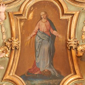 Zdjęcie nr 1: Obraz w kształcie stojącego prostokąta, umieszczony w ramie o potrójnie wklęsłej podstawie, wklęsłych bokach, zamkniętej łukiem nadwieszonym. W centrum kompozycji ukazana jest Matka Boska, frontalnie, stojąca na globie ziemskim, stopami depcząca węża. Lewa noga Marii ugięta w kolanie, oparta na głowie węża, ręce rozłożone na boki, od których odchodzą złote promienie, głowa przechylona delikatnie na prawą stronę. Twarz Marii pełna, usta drobne, oczy przymknięte, wysokie czoło. Włosy długie i jasne z przedziałkiem pośrodku, spływające na plecy; wokół głowy wieniec z dwunastu gwiazd. Matka Boska ubrana jest w długą, różową suknię z długimi rękawami, przewiązaną w talii oraz ciemnoniebieski płaszcz zarzucony na plecy i prawą połą zasłaniający nogi. Tło jednolite, ugrowe. Kolorystyka ciepła i pastelowa. 