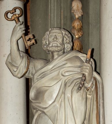 Zdjęcie nr 1: Rzeźba ścięta z tyłu, drążona, przedstawiająca św. Piotra. Święty ukazany jest w postawi stojącej, frontalnie  w delikatnym kontrapoście z prawą ręką uniesioną wysoko do góry, a lewą ugiętą w łokciu, w obu trzyma klucze. Twarz szeroka, okolona krótką brodą, nos długi, usta delikatnie rozchylone. Włosy średniej długości, sięgające za uszy, bujne. Święty ubrany jest w długą suknię z rękawami podwiniętymi do łokci oraz obszerny płaszcz zarzucony na lewe ramię i otaczający całą postać. Szaty na brzegach zdobione złotą lamówką. Rzeźba polichromowana na biało, atrybuty i brzeg szaty złocone.