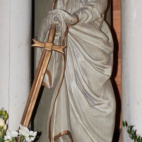 Zdjęcie nr 1: Rzeźba ścięta z tyłu, drążona, przedstawiająca św. Pawła. Święty ukazany jest w postawie stojącej z prawą nogą wysuniętą do przodu o esowato wygiętej sylwetce z dłońmi opartymi o miecz przy prawym boku. Twarz podłużna, okolona długą brodą, nos długi, głęboko osadzone oczy i wyraźnie zaznaczone kości policzkowe i łuki brwiowe. Włosy średniej długości, bujne. Święty ubrany jest w długą suknię oraz płaszcz zarzucony na prawe ramię i biegnący pod lewą ręką na prawe przedramię. Szaty na brzegach zdobione są złotą lamówką. Rzeźba polichromowana jest w całości na biało, atrybuty i brzeg szaty złocone. Rzeźba ustawiona jest na wysokim, prostopadłościennym cokole, zwężonym pośrodku, bogato profilowanym, polichromowanym na kolor jasnozielony.