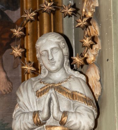 Zdjęcie nr 1: Rzeźba Matki Boskiej Niepokalanie Poczętej ustawiona frontalnie na globie ziemskim. Maria ma ręce złożone w geście modlitwy. Twarz owalna, pełna z dużym nosem i wyraźnie zaznaczonym podbródkiem. Włosy długie, bujne, opadające na ramiona i plecy. Maria ubrana jest w długą suknię, złoconą na brzegach rękawów i przewiązaną w talii złotym paskiem oraz płaszcz założony na prawe ramię o złoconej lamówce. Glob ziemski oplata wąż, malowany na złoto. Figura polichromowana na biało, detale złocone. Maria wokół głowy ma wieniec z dziewięciu gwiazd umieszczonych na metalowej obręczy.