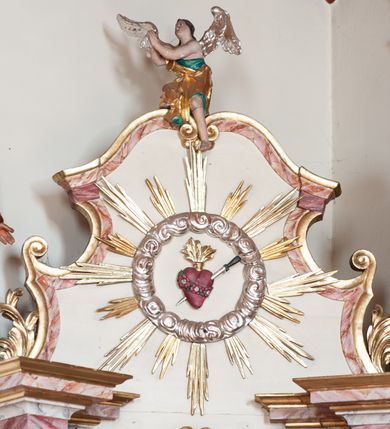 Zdjęcie nr 9: Ołtarz przyścienny, architektoniczny, jednoosiowy, jednokondygnacyjny ze zwieńczeniem. Ołtarz skrzyniowy, antepedium drewniane z wydzielonym polem w kształcie lezącego ośmioboku z dekoracją w formie marmoryzacji. Mensa drewniana, polichromowana. Retabulum ustawione na wysokim, zdwojonym cokole, ujęte parą kolumn korynckich wspierających przerwane, wyłamujące się belkowanie z profilowanym, silnie wysuniętym gzymsem. Zwieńczenie o formie wklęsło-wypukłej, flankowane spływami wolutowymi. Prostokątne pola cokołów kolumn dekorowane motywem roślinnym. Pole środkowe w formie prostokątnej wnęki zamkniętej fantazyjnym łukiem nadwieszonym ujętym stylizowanymi motywami roślinnymi, z dwoma uskrzydlonymi główkami aniołków pośrodku. Wewnątrz figura Matki Boskiej Niepokalanie Poczętej. W zwieńczeniu po bokach dwie pełnoplastyczne figury świętych (po lewej św. Jakub Większy z bukłakiem u boku), w polu motyw serca przeszytego mieczem boleści, ujętego okręgiem obłoków i promieni. Powyżej na gzymsie figurka anioła. Polichromia całości struktury w kolorze kremowym. Pola płycin, kolumny, elementy belkowania, obramienie niszy marmoryzowane. Detal architektoniczny i ornamenty złocone i srebrzone.  
