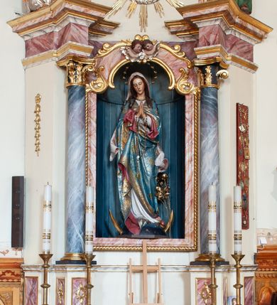Zdjęcie nr 1: Ołtarz przyścienny, architektoniczny, jednoosiowy, jednokondygnacyjny ze zwieńczeniem. Ołtarz skrzyniowy, antepedium drewniane z wydzielonym polem w kształcie lezącego ośmioboku z dekoracją w formie marmoryzacji. Mensa drewniana, polichromowana. Retabulum ustawione na wysokim, zdwojonym cokole, ujęte parą kolumn korynckich wspierających przerwane, wyłamujące się belkowanie z profilowanym, silnie wysuniętym gzymsem. Zwieńczenie o formie wklęsło-wypukłej, flankowane spływami wolutowymi. Prostokątne pola cokołów kolumn dekorowane motywem roślinnym. Pole środkowe w formie prostokątnej wnęki zamkniętej fantazyjnym łukiem nadwieszonym ujętym stylizowanymi motywami roślinnymi, z dwoma uskrzydlonymi główkami aniołków pośrodku. Wewnątrz figura Matki Boskiej Niepokalanie Poczętej. W zwieńczeniu po bokach dwie pełnoplastyczne figury świętych (po lewej św. Jakub Większy z bukłakiem u boku), w polu motyw serca przeszytego mieczem boleści, ujętego okręgiem obłoków i promieni. Powyżej na gzymsie figurka anioła. Polichromia całości struktury w kolorze kremowym. Pola płycin, kolumny, elementy belkowania, obramienie niszy marmoryzowane. Detal architektoniczny i ornamenty złocone i srebrzone.  
