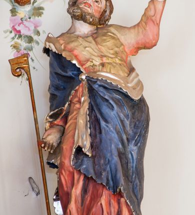 Zdjęcie nr 9: Ołtarz przyścienny, architektoniczny, trójosiowy. Mensa ołtarzowa skrzyniowa, prostopadłościenna z kamiennym portatylem, zamknięta profilowanym gzymsem podtrzymywanym przez cztery marmoryzowane kolumny. Antepedium dekorowane trzema płycinami: środkowa kwadratowa z krzyżem trójlistnym w czworoliściu, boczne  z aplikowanym motywem winorośli i kłosów zbóż. Retabulum ustawione na predelli, trójosiowe o półkoliście zamkniętych wnękach zakończonych trójkątnymi szczytami, w polu których uskrzydlone główki anielskie w medalionach. Wnęka środkowa wyższa i szersza zamknięta dwuspadowym daszkiem, ujęta parą kolumn kompozytowych wspierających odcinki gzymsu. Wewnątrz obraz z przedstawieniem  św. Rozalii. We wnękach bocznych pełnoplastyczne figury św. Piotra po lewej i św. Pawła po prawej stronie.  Nad wnęką środkową baldachim z figurą Chrystusa Zmartwychwstałego, po bokach pełnoplastyczne figury świętych. Predella dekorowana fryzem arkadkowym oraz płycinami z maswerkowaniem i rozetami, boki retabulum ujęte ażurowymi uszakami formowanymi z wici roślinnej. Półkoliste łuki wnęk zdobione arkadkami. Całość polichromowana na odcień ciemnobrązowy, detal architektoniczny i profilowania pomarańczowe oraz złocone. 