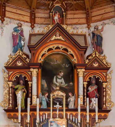 Zdjęcie nr 1: Ołtarz przyścienny, architektoniczny, trójosiowy. Mensa ołtarzowa skrzyniowa, prostopadłościenna z kamiennym portatylem, zamknięta profilowanym gzymsem podtrzymywanym przez cztery marmoryzowane kolumny. Antepedium dekorowane trzema płycinami: środkowa kwadratowa z krzyżem trójlistnym w czworoliściu, boczne  z aplikowanym motywem winorośli i kłosów zbóż. Retabulum ustawione na predelli, trójosiowe o półkoliście zamkniętych wnękach zakończonych trójkątnymi szczytami, w polu których uskrzydlone główki anielskie w medalionach. Wnęka środkowa wyższa i szersza zamknięta dwuspadowym daszkiem, ujęta parą kolumn kompozytowych wspierających odcinki gzymsu. Wewnątrz obraz z przedstawieniem  św. Rozalii. We wnękach bocznych pełnoplastyczne figury św. Piotra po lewej i św. Pawła po prawej stronie.  Nad wnęką środkową baldachim z figurą Chrystusa Zmartwychwstałego, po bokach pełnoplastyczne figury świętych. Predella dekorowana fryzem arkadkowym oraz płycinami z maswerkowaniem i rozetami, boki retabulum ujęte ażurowymi uszakami formowanymi z wici roślinnej. Półkoliste łuki wnęk zdobione arkadkami. Całość polichromowana na odcień ciemnobrązowy, detal architektoniczny i profilowania pomarańczowe oraz złocone. 