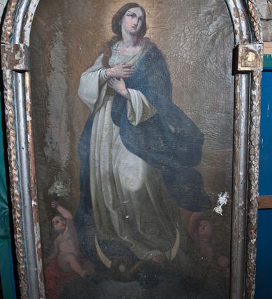 Zdjęcie nr 2: Obraz w kształcie stojącego prostokąta zamkniętego łukiem półkolistym. W centrum kompozycji przedstawienie Matki Boskiej Niepokalanie Poczętej, stojącej na półksiężycu i globie, ze złączonymi na piersi dłońmi. Maria zwrócona delikatnie w prawo, ukazana w kontrapoście z lewą nogą ugiętą w kolanie i z głową skierowaną w lewą stronę. Twarz pełna z długim i wąskim nosem, małymi ustami i z oczami wzniesionymi ku górze; włosy ciemne, długie, bujne, opadające na plecy i prawe ramię. Matka Boska ubrana jest w białą suknię z długimi i szerokimi rękawami oraz niebieski płaszcz zarzucony na lewe ramię. Ma bose stopy, a wokół głowy świetlisty nimb. Półksiężyc skierowany jest rogami do góry, owinięty wężem z jabłkiem w pysku. Po bokach Matki Boskiej dwa aniołki, jeden z gałązką białej lilii w dłoni. Na globie ziemskim dwie główki aniołków. Tło jednolite jasnobrązowe. Rama drewniana, ołtarzowa, profilowana, złocona i srebrzona. Na zewnętrznym profilu ozdobiona wicią z liści wawrzynu, a w kluczu okrągłym kartuszem.



