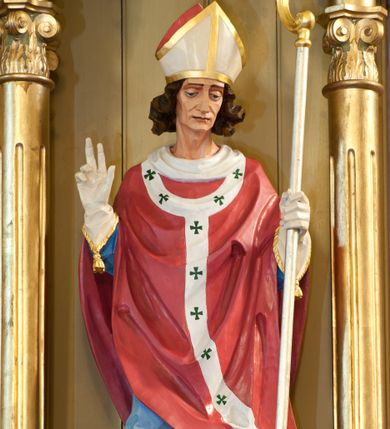 Zdjęcie nr 1: Rzeźba św. Stanisława wydrążona z tyłu, ustawiona na niskim cokole. Święty ukazany w pozycji stojącej, frontalnie, w lekkim kontrapoście, w lewej dłoni trzyma pastorał, a prawą czyni gest oratorski. Twarz szeroka o ostrych rysach, dużych i głęboko osadzonych oczach, długim nosie, bez zarostu. Włosy średniej długości, brązowe, bujne, zasłaniające uszy. Święty jest ubrany w niebieską albę, czerwony ornat i paliusz. Na dłoniach ma białe rękawiczki, na głowie biało-złotą infułę, na stopach brązowe buty. U jego stóp rzeźba przedstawiająca Piotrowina, ukazująca tylko głowę i prawą dłoń. Twarz Piotrowina podłużna, okolona bujną brodą, z długim i prostym nosem, ma założoną na głowę białą szatę, dekorowaną kolorowymi paskami. Polichromia w odsłoniętych partiach ciała naturalistyczna, detale złocone i srebrzone.