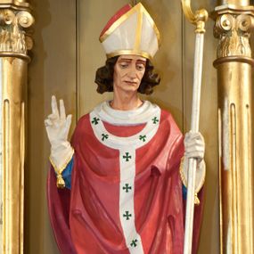 Zdjęcie nr 1: Rzeźba św. Stanisława wydrążona z tyłu, ustawiona na niskim cokole. Święty ukazany w pozycji stojącej, frontalnie, w lekkim kontrapoście, w lewej dłoni trzyma pastorał, a prawą czyni gest oratorski. Twarz szeroka o ostrych rysach, dużych i głęboko osadzonych oczach, długim nosie, bez zarostu. Włosy średniej długości, brązowe, bujne, zasłaniające uszy. Święty jest ubrany w niebieską albę, czerwony ornat i paliusz. Na dłoniach ma białe rękawiczki, na głowie biało-złotą infułę, na stopach brązowe buty. U jego stóp rzeźba przedstawiająca Piotrowina, ukazująca tylko głowę i prawą dłoń. Twarz Piotrowina podłużna, okolona bujną brodą, z długim i prostym nosem, ma założoną na głowę białą szatę, dekorowaną kolorowymi paskami. Polichromia w odsłoniętych partiach ciała naturalistyczna, detale złocone i srebrzone.