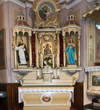 Zdjęcie nr 1: Ołtarz przyścienny, architektoniczny, trójosiowy, jednokondygnacyjny ze zwieńczeniem. Ołtarz skrzyniowy, sarkofagowy, z kamiennym portatylem. Mensa wklęsło-wypukła, z wydzielonym polem, pośrodku którego, ujęte okrągłą ramą płaskorzeźbione, polichromowane gorejące serce. Tabernakulum w formie prostopadłościennej skrzynki, ustawione na niskim cokole, ujęte parą lizen zdobionych cekinami, zamknięte profilowanych gzymsem. Drzwiczki dekorowane płyciną w kształcie stojącego prostokąta, zamkniętego łukiem półkolistym, w polu z płaskorzeźbioną winną latoroślą i kłosami zbóż na zielonym tle. Retabulum ustawione na wysokim cokole, kształtowanym schodkowo. Osie boczne retabulum w formie ażurowych, architektonicznych tempiett, o profilowanych wielobocznych podstawach z pięciobocznym podwieszeniem. Baldachimy, wsparte na parze kolumn, kształtowane są na wzór architektonicznych dachów, z wycięciem arkadkowym u dołu oraz ze zwieńczeniem w formie wielobocznej latarni zakończonej kwiatonem. W niszy po lewej figura św. Jacka, a po prawej św. Kazimierza królewicza. Część środkowa retabulum flankowana parą kolumn wspierających wyłamane pośrodku niepełne belkowanie. W polu obraz Matki Boskiej Nieustającej Pomocy, dookoła dekorowany bujnym ornamentem akantowym i stylizowaną muszlą u góry, po bokach na czerwonym tle zawieszone liczne wota. Zwieńczenie w formie owalu ujętego dekoracyjną ramą z obrazem św. Józefa. U szczytu rzeźbiona, uskrzydlona główka aniołka i łaciński krzyż. Polichromia w kolorze jasnobeżowym, detale zielone, profilowania i ornamentyka złocone.