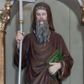 Zdjęcie nr 1: Rzeźba pełnoplastyczna przedstawiająca św. Cyryla, ustawiona na niskim cokole. Figura ustawiona frontalnie, w lewej ręce trzyma księgę, w prawej krzyż. Twarz pociągła, długi i szeroki nos, oczy skierowane na wprost, okolona bujną, siwą i długą brodą. Święty jest ubrany w brązową togę filozofa z długimi rękawami i kapturem założonym na głowę, obwiedzioną na brzegach stylizowaną wicią roślinną, pod spodem ma białą, długą suknię. Księga w zielonej obwolucie, z krzyżykiem greckim na okładce. Polichromia naturalistyczna w odsłoniętych partiach ciała, detale złocone i srebrzone.
